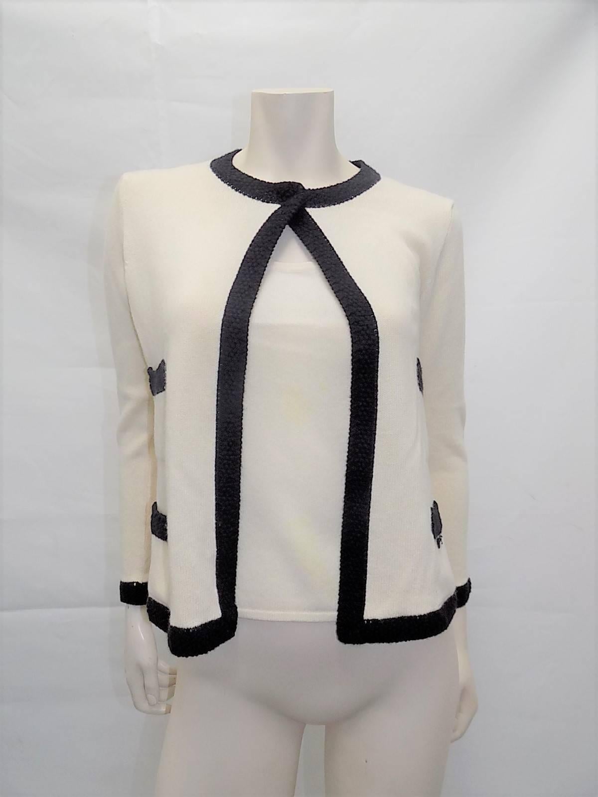 Collection 2003 in mint condition beautiful Chanel sweater set.  Ivory Cashmere with black crochet trim. Sleeveless top and sweater with one snap closure on the neckline. Four front patch pockets . Small Chanel plaque on the pocket. Size 40
Bust