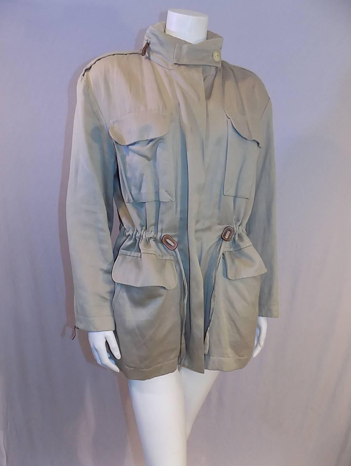 Amazing tailoring and craftsmanship on this safari jacket by Hermes.  No visible  seems inside or out . Stored hood in zippered compartment at the neckline. zip front closure. draw string  waistline Natural color leather details , Four front