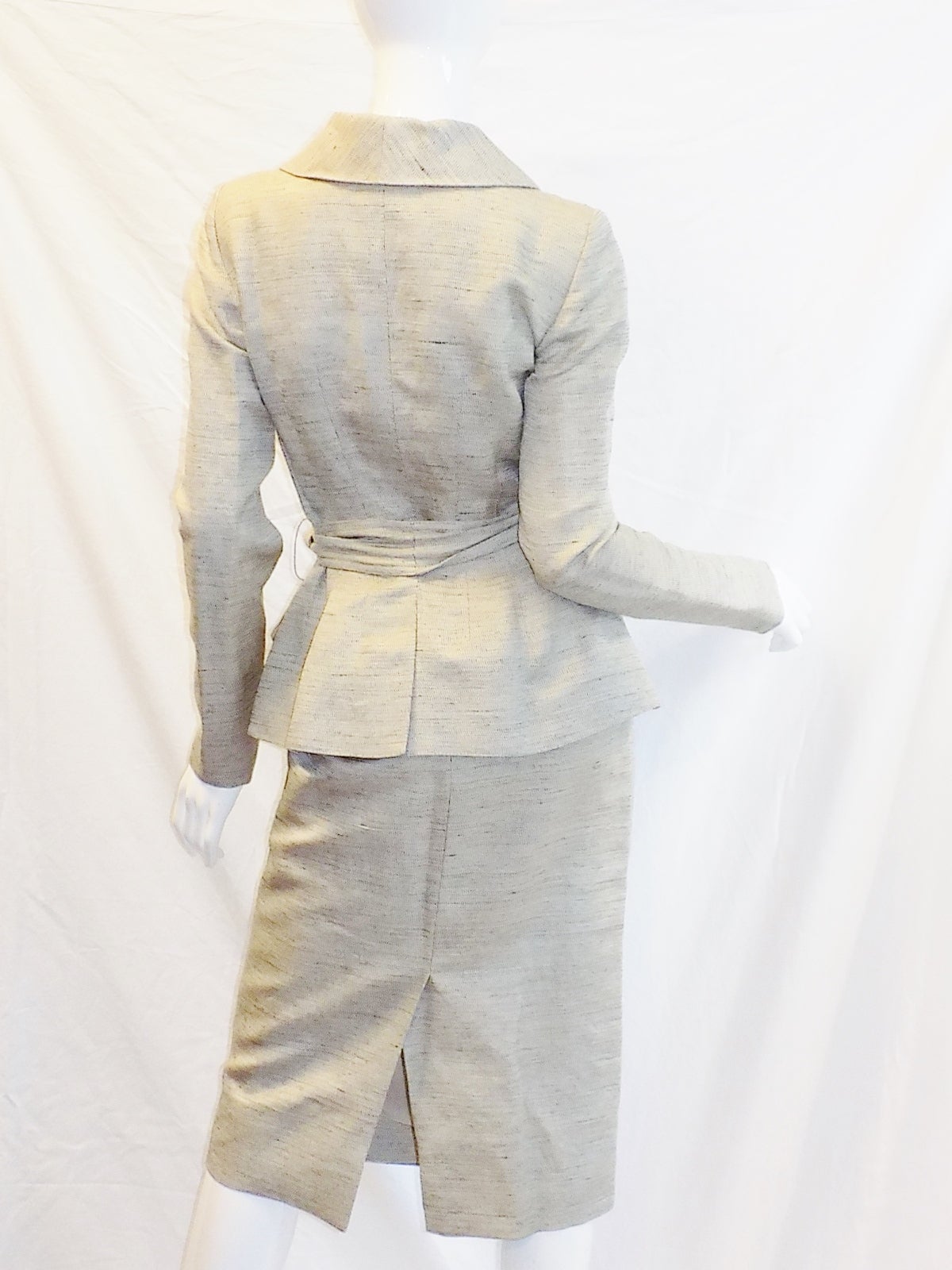 New and absolutely a must have for that powerful executive sharp woman. Raw silk all silk lined. Fitted jacket featuring shawl collar, soft belt and side snap closure. Midi pencil skirt. Cut and fitted to perfection. This suit is showroom sample.