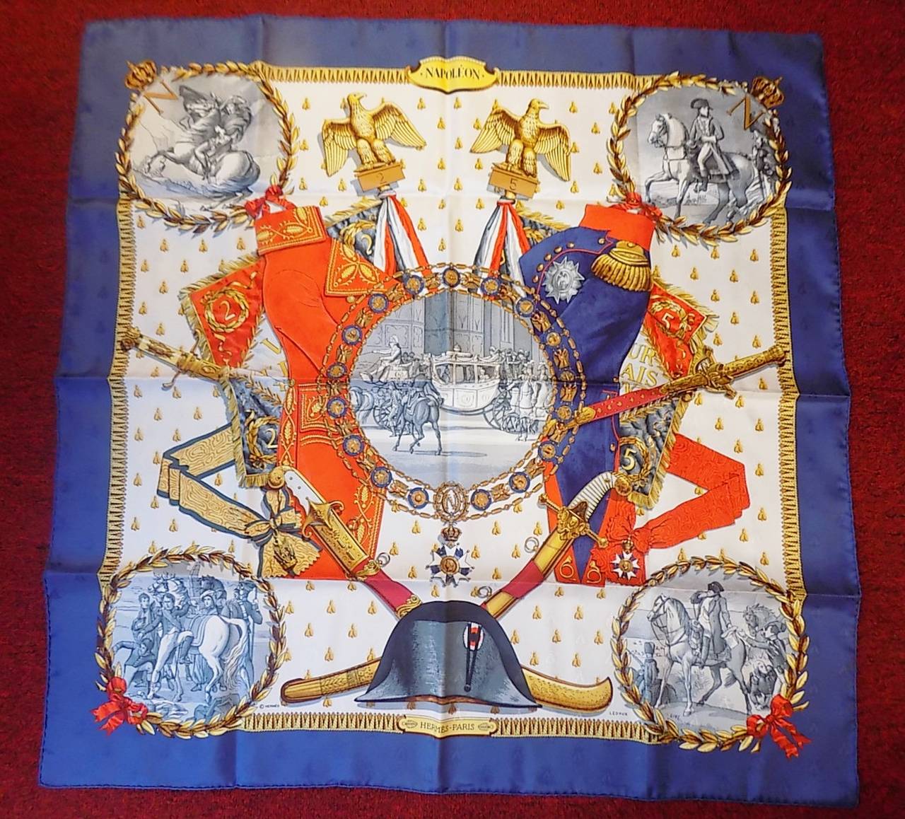 This is a  A must-have for any Hermès scarf collection.  Rich navy blue  border  with red and gold . Philippe Ledoux’s 1963 Napoleon is the quintessential Hermès scarf. The emperor’s beloved bees are screened onto the scarf as part of the design