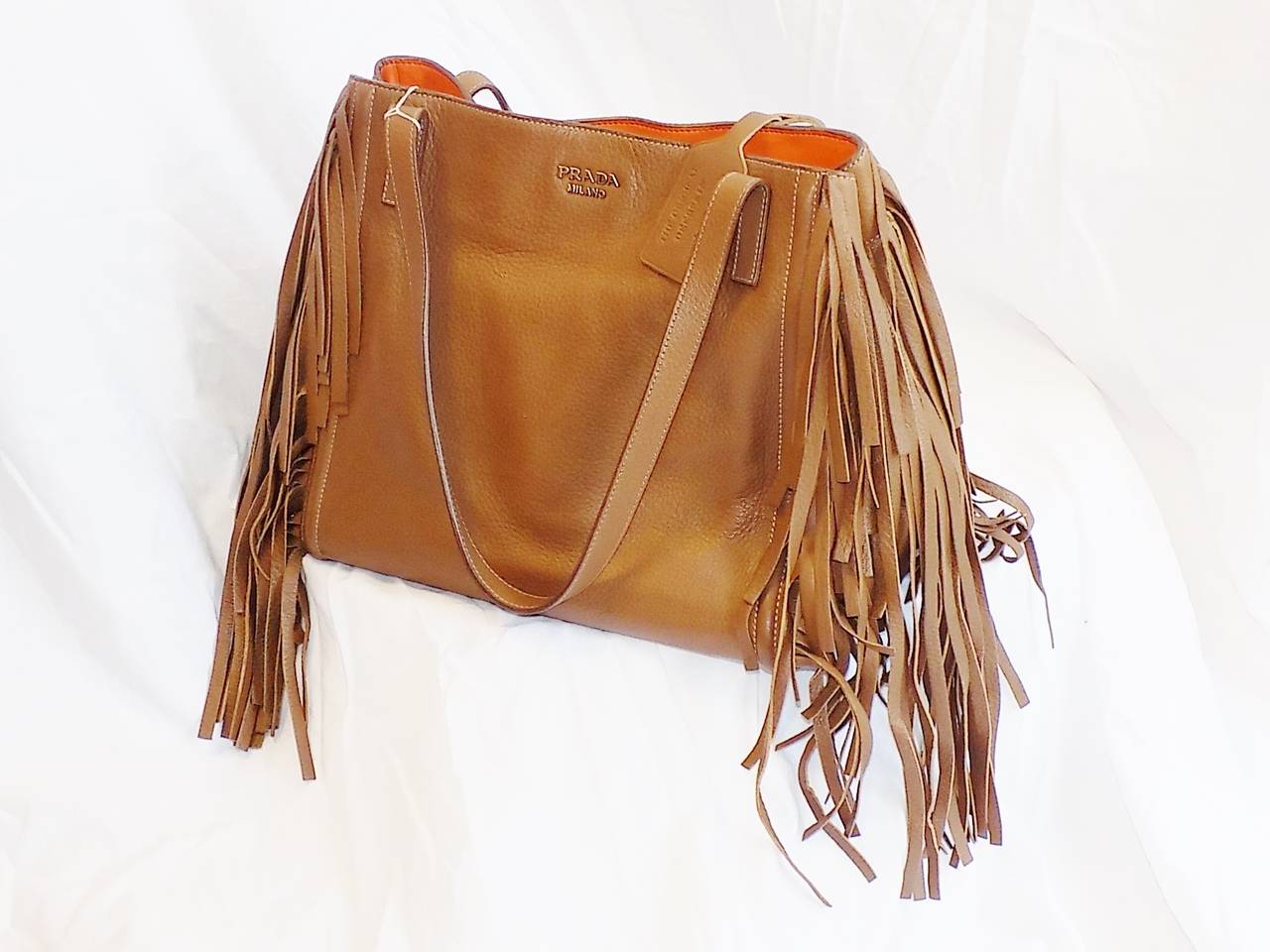 New with all authenticity cards beautiful Prada tote bag.  Deer skin Fringed Shoulder bag with supple orange leather lining. Double shoulder strap. Snap closure . Featuring gold tone vintage hardware and plenty of zip pockets as well as phone and