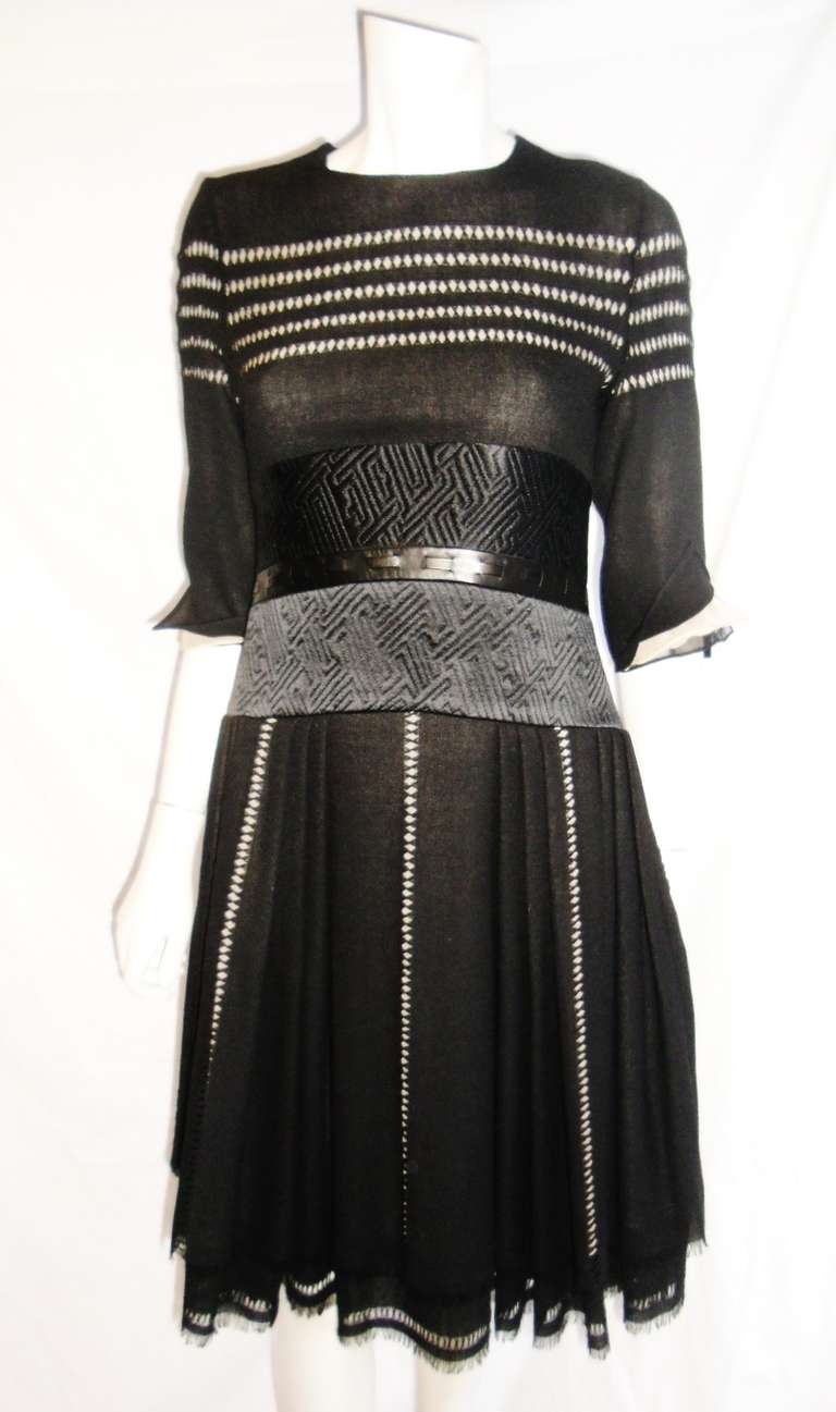 Wool crepe lined in silk chiffon with so much intricate work.  Round neckline, diamond  shaped eyelet, quilted silk midsection  adorned with leather . Pleated ull skirt with fringed bottom. It all sounds too much put put together with so much style