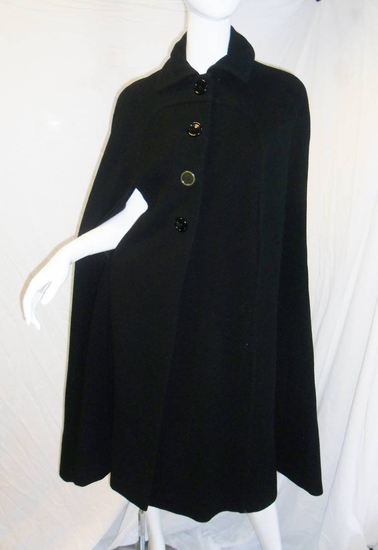 Beautiful vintage black wool  cape featuring  lager front buttons closure , collar and slits for arms. Circa 1970.
States size 10 but small . length 45 inches. One button is slightly discolored due to age. Rest of the cape is excellent condition.