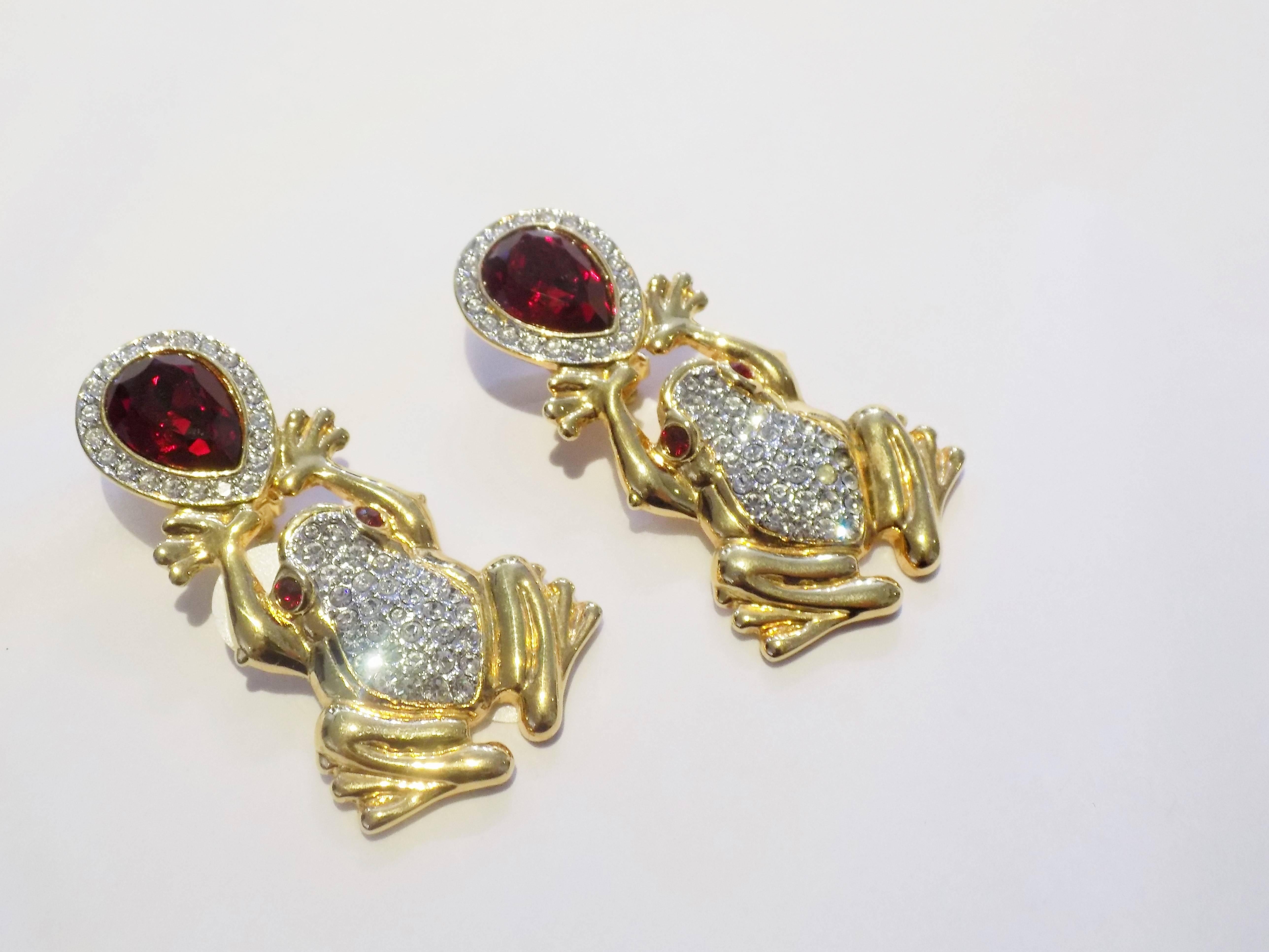 Spectacular Valentino Vintage frog earrings. Gold tone metal with clear crystals simulating diamonds with red eyes  holding pear shaped large red crystal as ruby. Earrings are Clips and they measure approx 3" of which  frog is 2" and earr