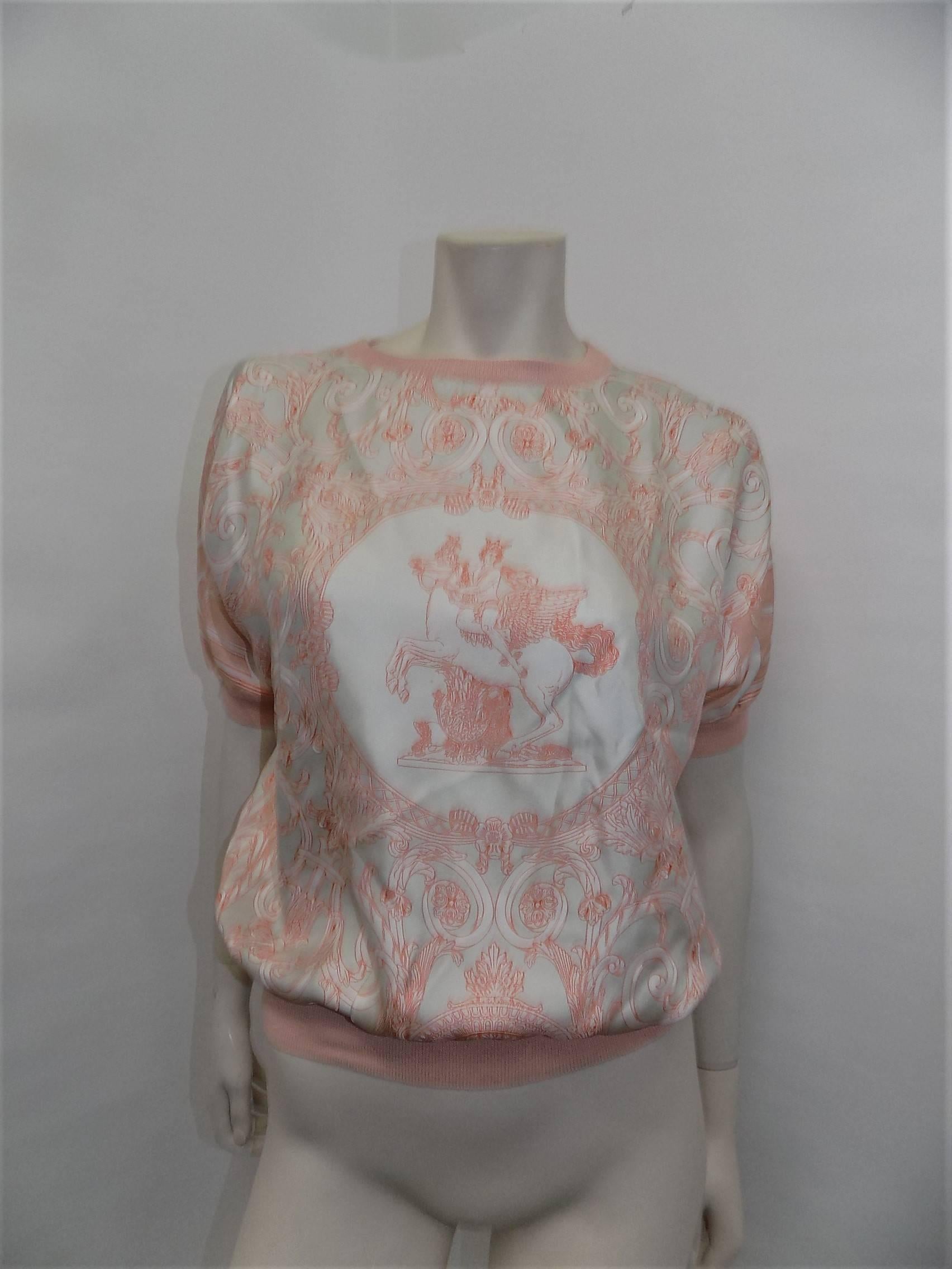 Spectacular and never worn pale peach blouse and cardigan set. Crew collared top with short sleeves and knit trim. Cardigan has double cuffs, gold toned buttons with Hermes Paris engraved details. Made in Italy. Top: 100% silk. Cardigan: 65%