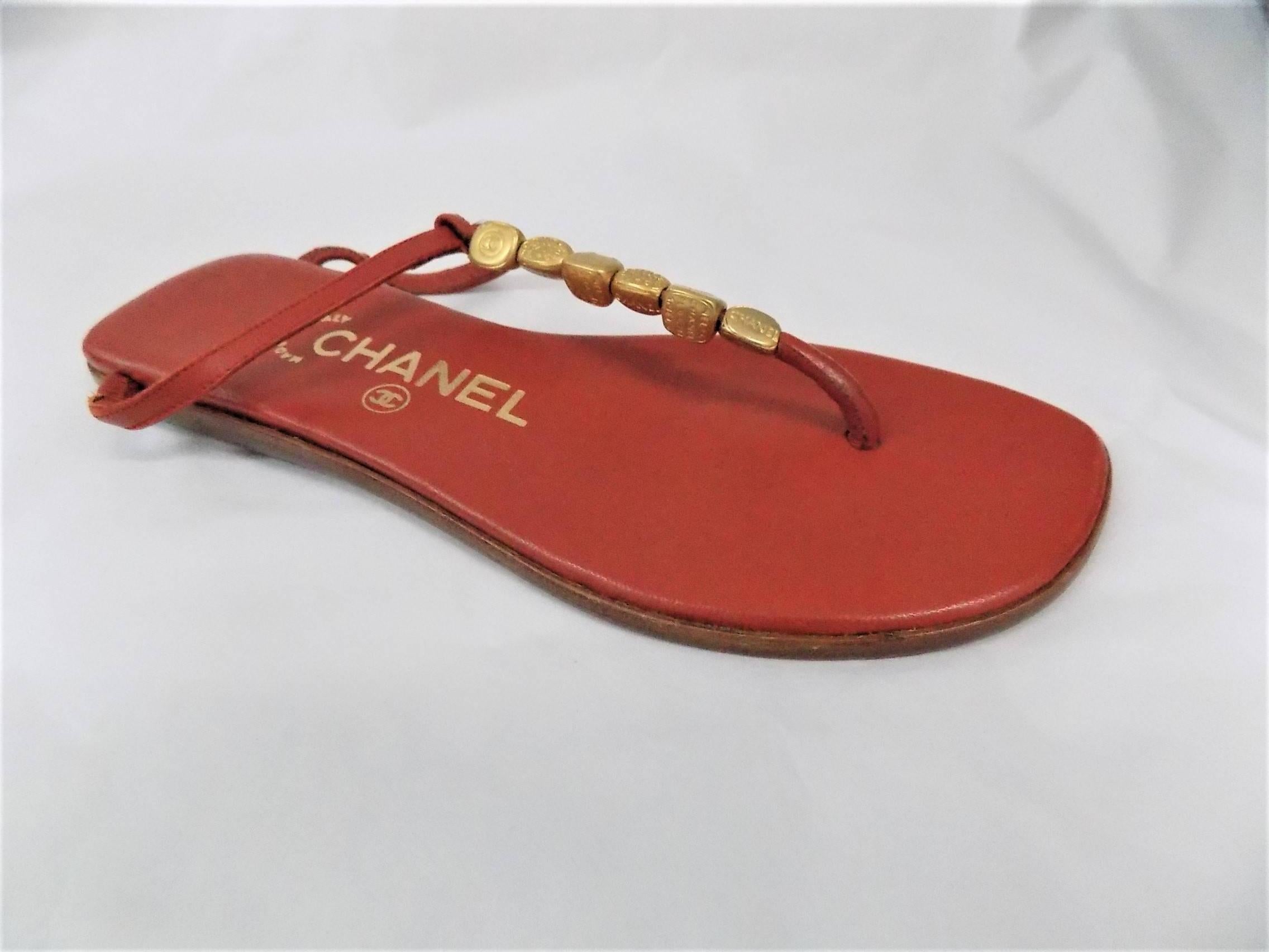 Red leather Chanel thong sandals with gold-tone logo bead embellishments, tonal stitching and stacked heels. Includes dust bag. Condition: Very Good. Faint wear at soles.Size 35
