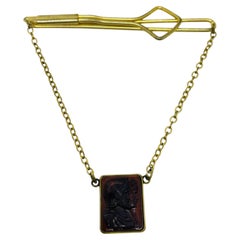 Alpineta vintage en tono dorado con cadena decorativa y intaglio de cristal romano en color rojo burdeos oscuro