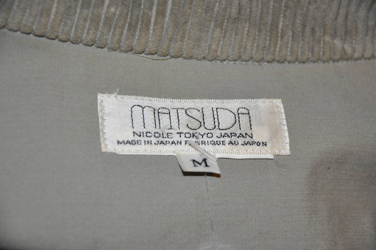 Matsuda men's olive green cotton button shirt is detailed with two removable patch zippered pockets in front. The center back is detailed with embroidered tab. Size Medium/Japan.
   The shoulder measures 22 1/2