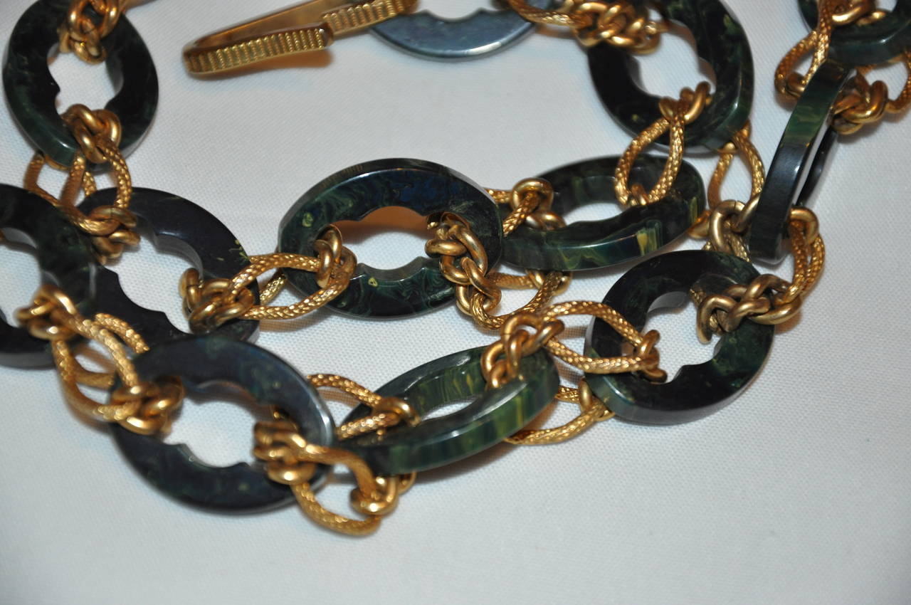 Este maravilloso herraje dorado se combina con cadenas de varios tamaños acentuadas con lucita verde. Este cinturón de cadena mide 36