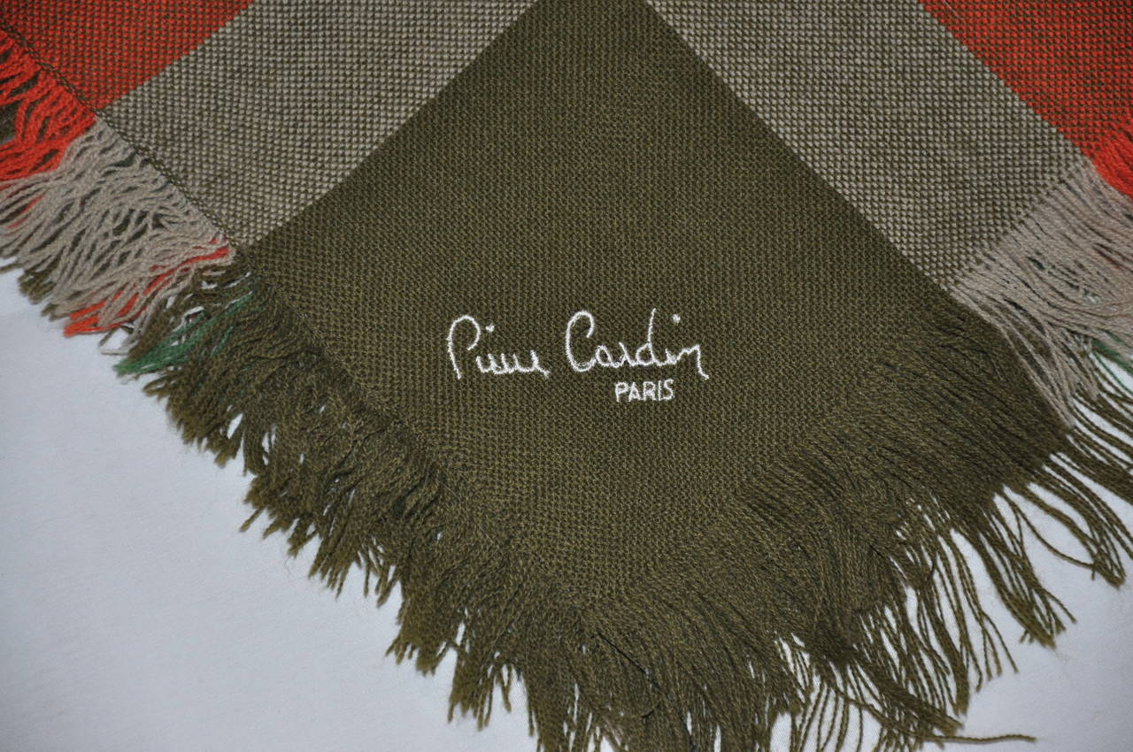 Pierre Cardin huge wool challis in multi-colors of greens, red, taupe and tan is finished with fringes on the edges. The scarf measures 50