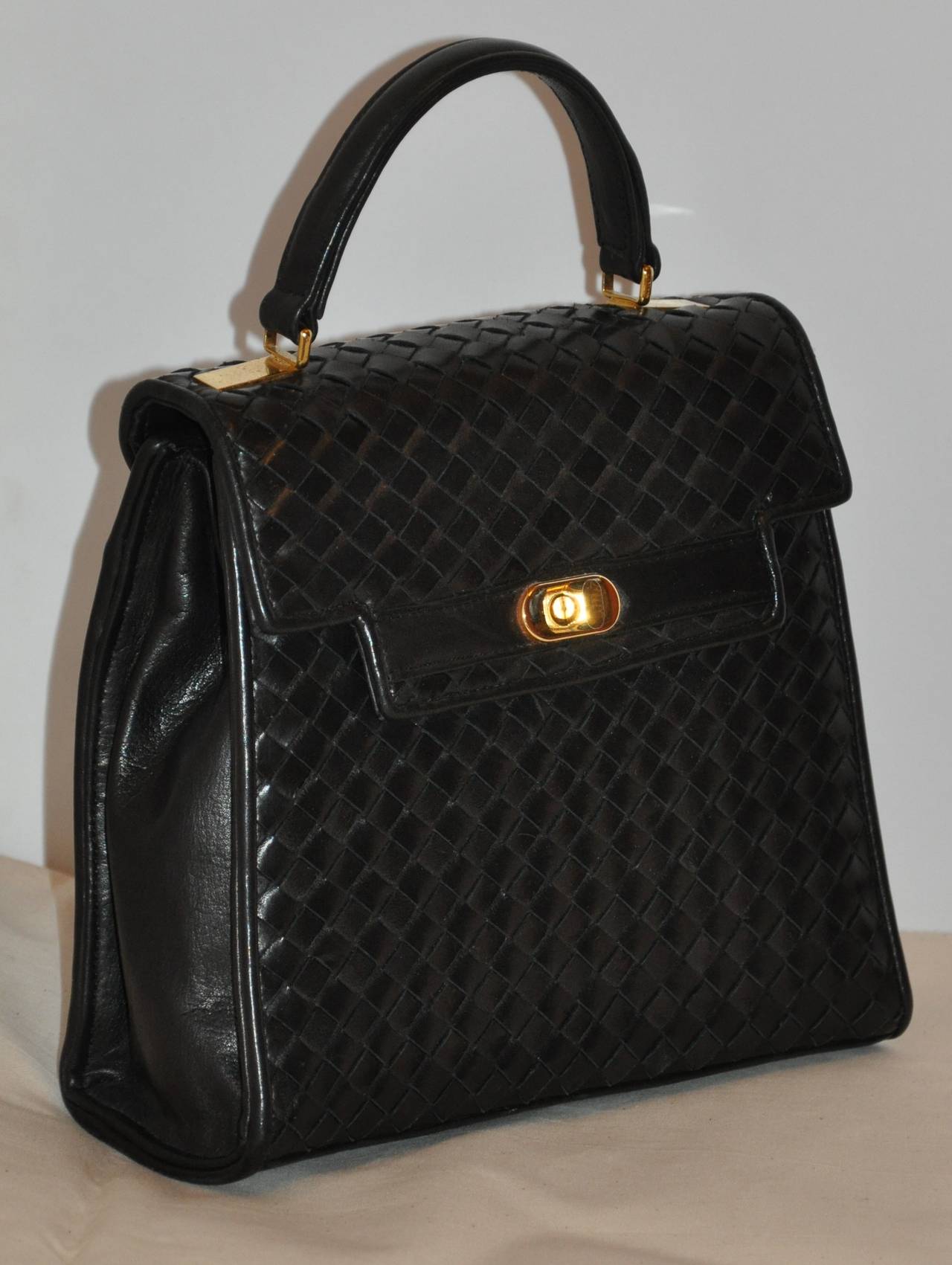 Saks Fifth Avenue black lambskin woven leather handbag has gold hardware and accented with an exterior compartment on the backside. 
   The handbag measures 8