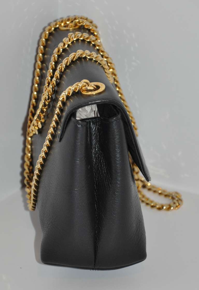 Paloma Piccaso black calfskin clutch and shoulder bag is accented with a heavy gold hardware chain strap which can be removed if desired. The interior has a zippered compartment. The exterior has her signature 