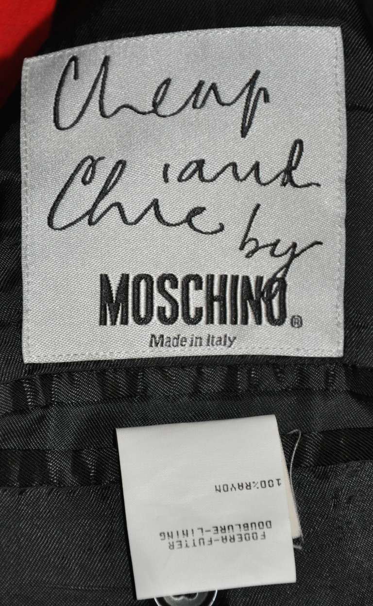 Der einreihige Herrenmantel aus motorroter Wolle von Moschino ist mit schwarzen Steppnähten versehen. Auf der Innenseite der vollständig gefütterten Jacke befinden sich zwei aufgesetzte Brusttaschen. Die Außenseite hat zwei eingesetzte Taschen auf