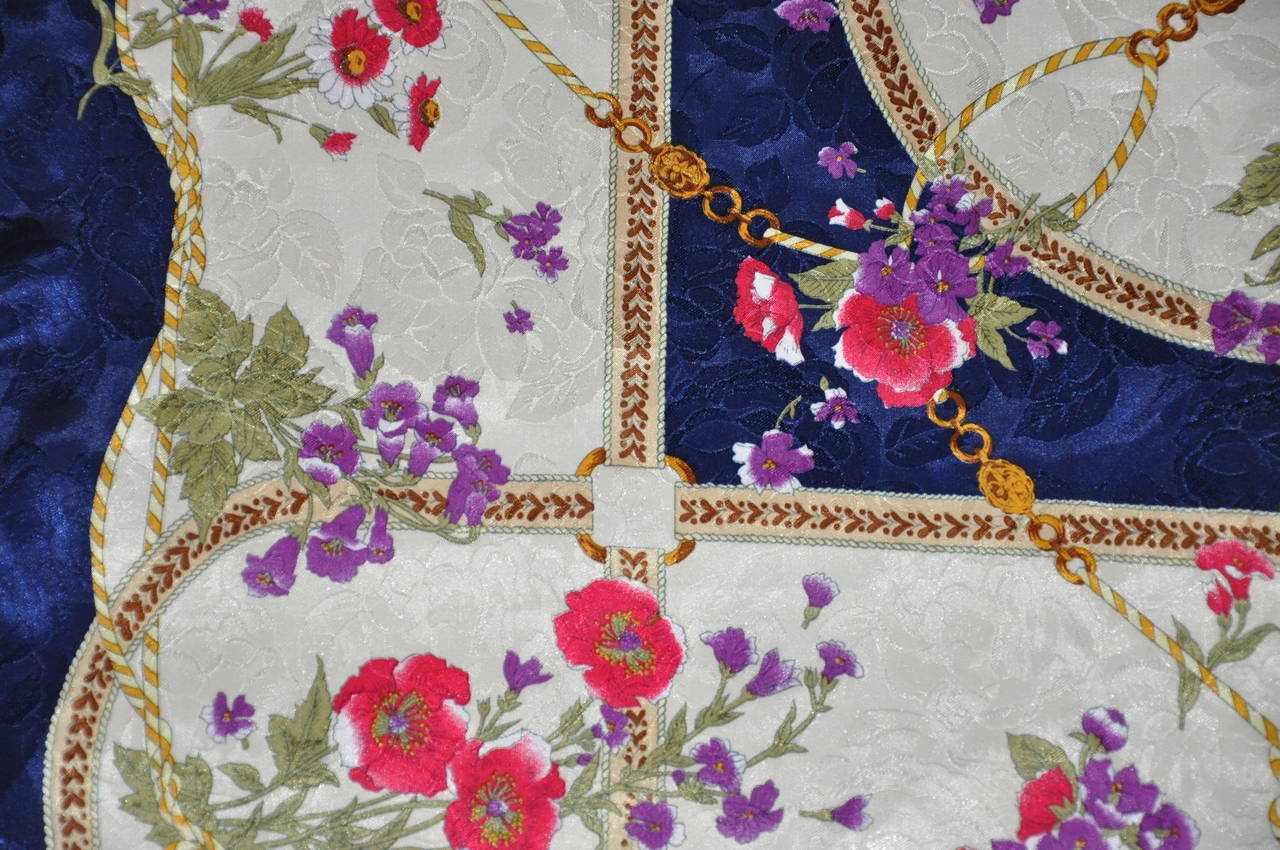 Este maravilloso y atrevido pañuelo de seda con estampado floral multicolor está acentuado con un ribete azul marino y acabado con bordes enrollados a mano y mide 30