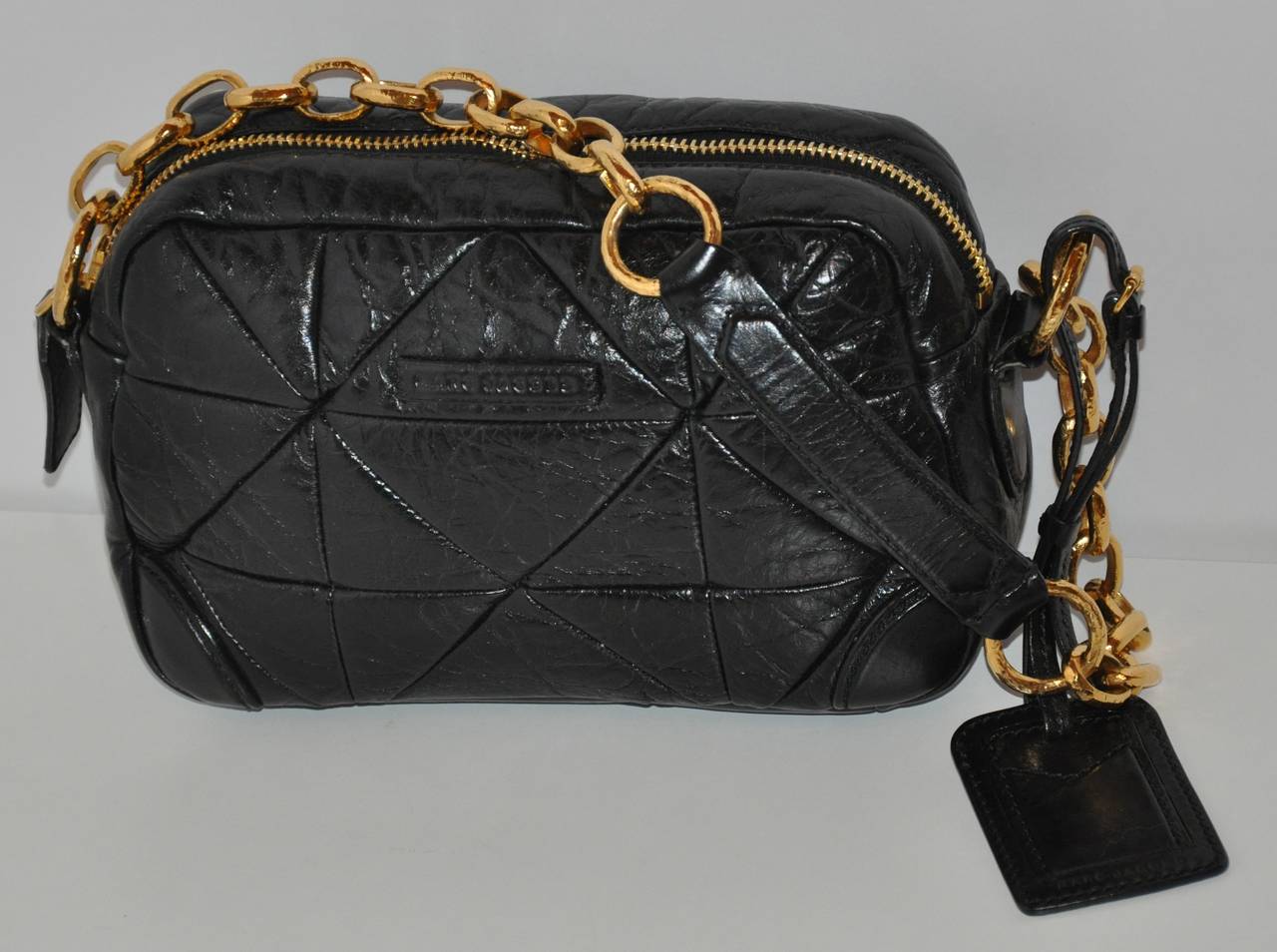 Marc Jacobs black calfskin quilted shoulder bag is accented with gilded gold hardware. The shoulder bag has a attached leather 