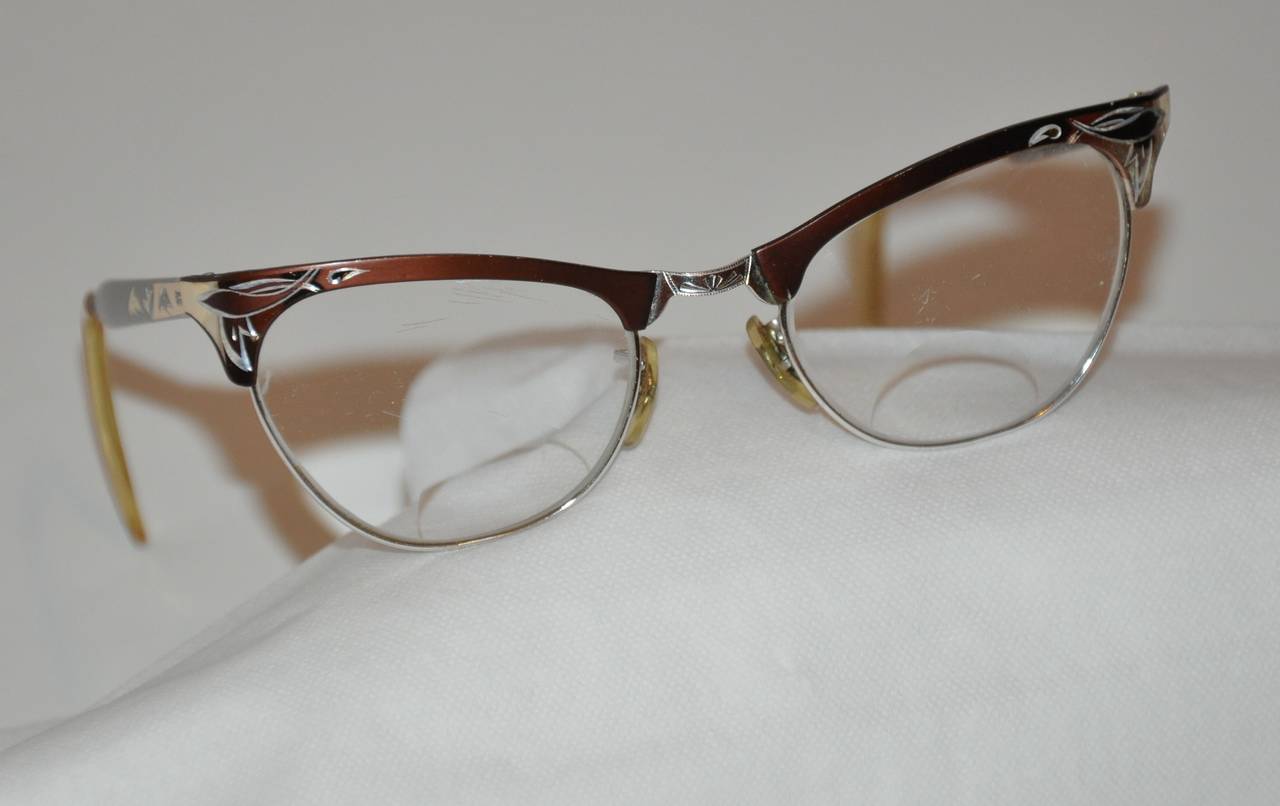 Vintage silver hardware frame Cat's Eyes eyeglasses are overlaid with bronze aluminium finish. The glasses are detailed with engraved etching of Leafs on the front corners as well as the center front and both arms. 
   The front measures 5