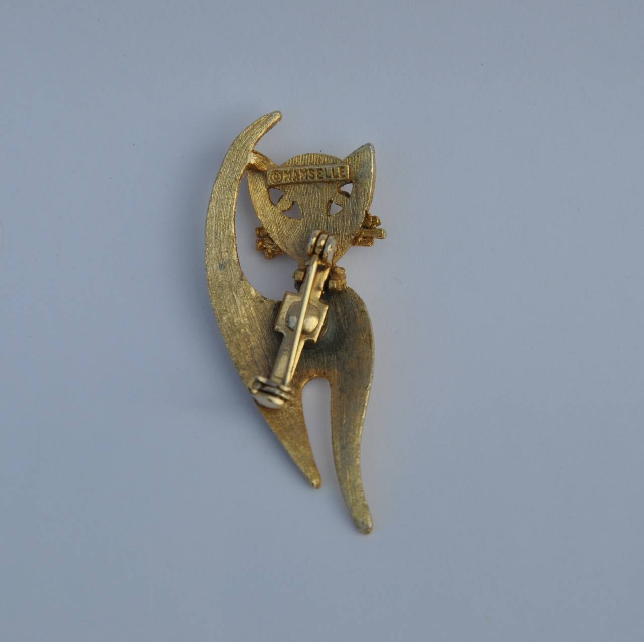Mamselle "Kitty Cat" brooch measures 7/8" in length, 2" in height and 2/8" in depth. Wonderfully detailed, the brooch is signed on the backside.