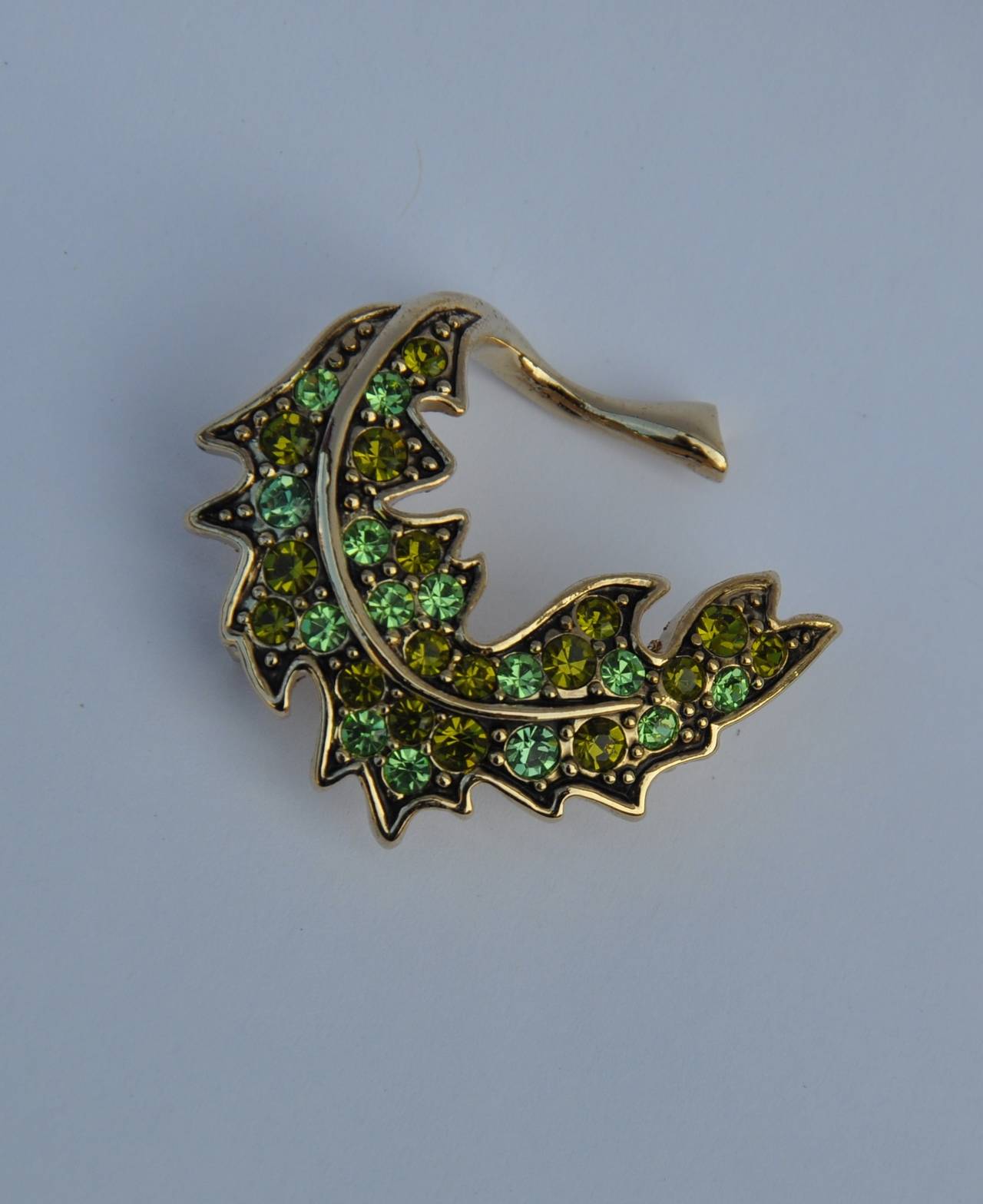 Trifari gilded gold vermeil finish with emerald green rhinestones "Leaf" brooch measures 1 5/8" in length across, 1 3/8" in height and 2/8" in depth.