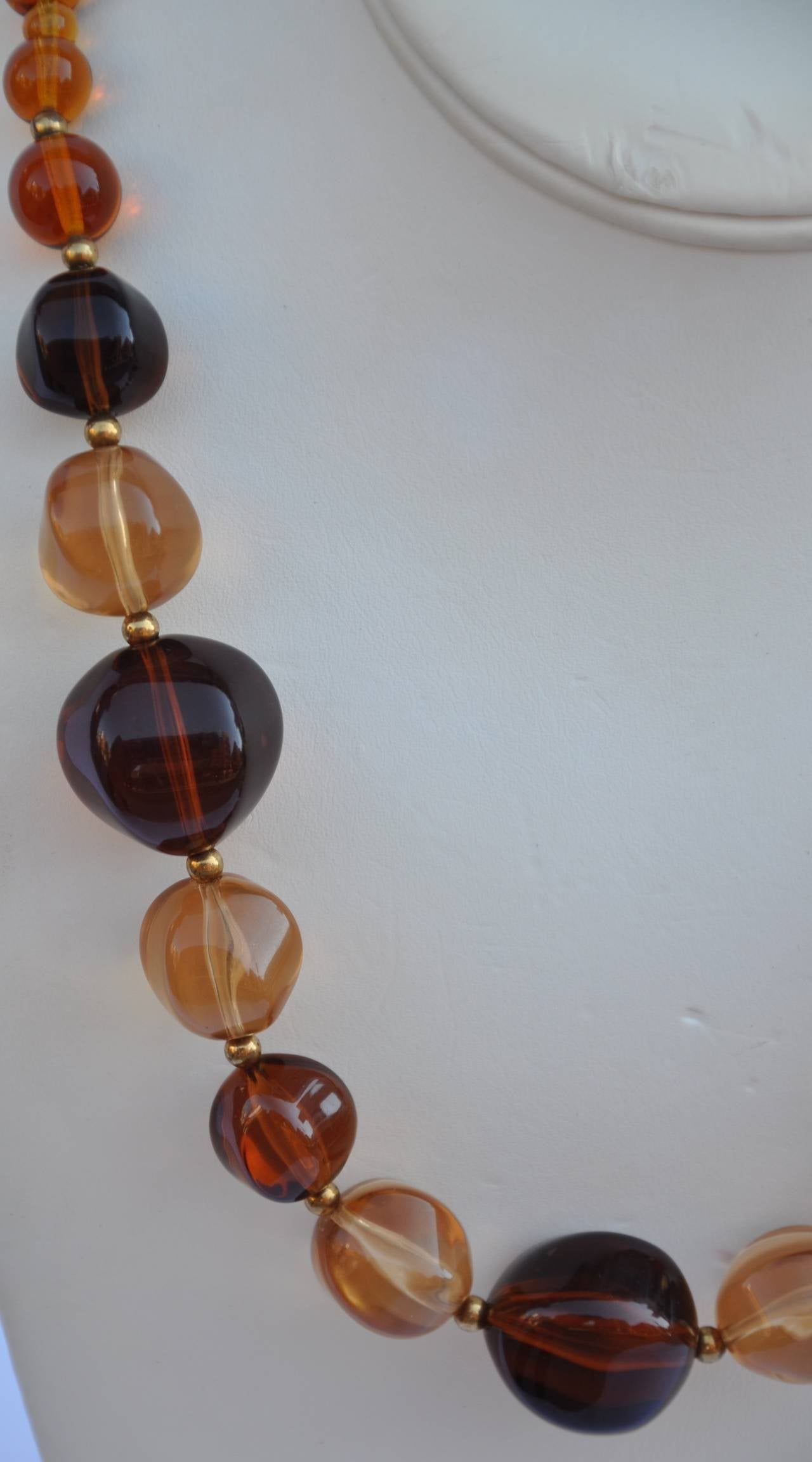 Multi-sizes of amber-tone lucite necklace measures 32". the widest width of the lucite measures 1".
