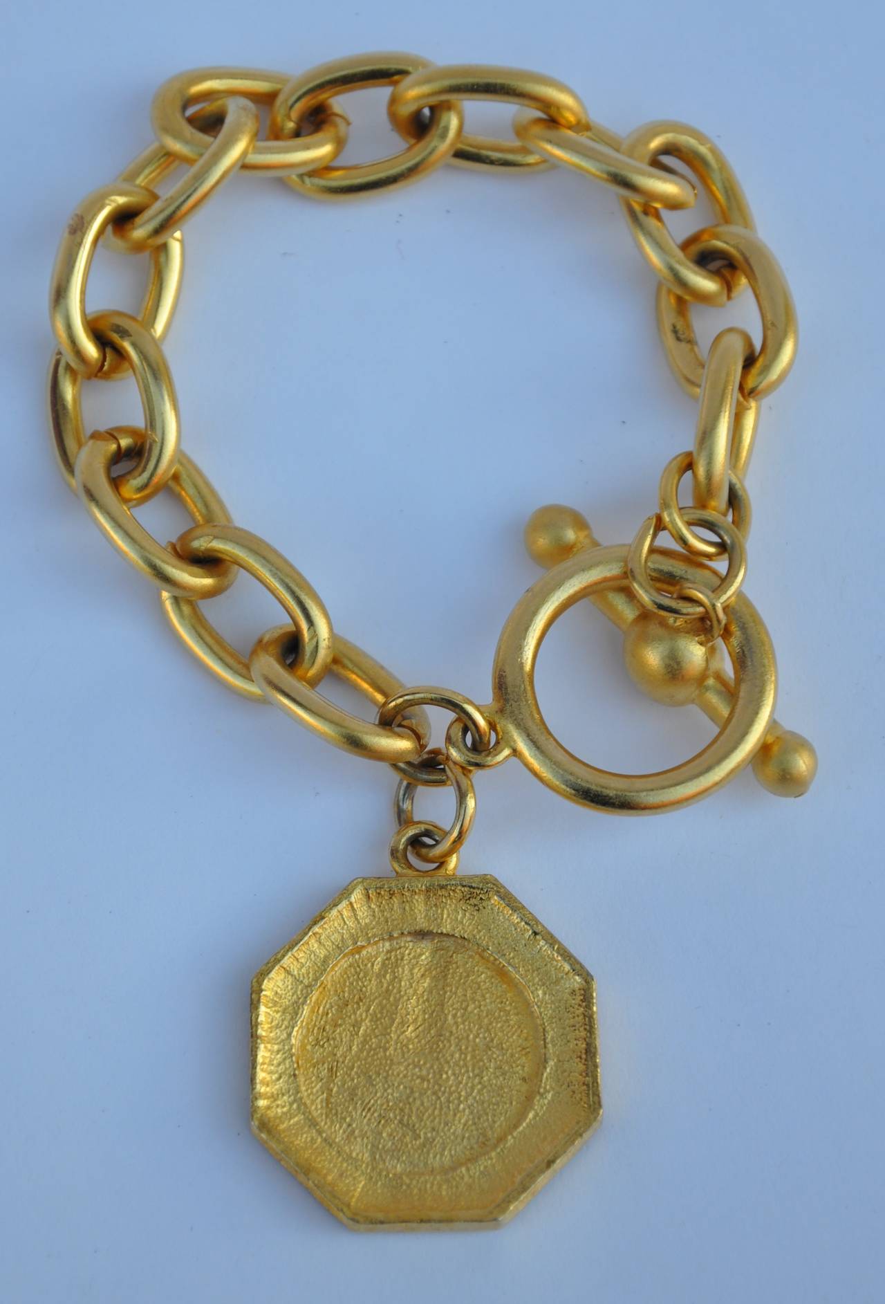 Gilded gold with vermeil finish chain bracelet is accented with a "Gold Coin". The bracelet measures 7 1/2" in length, width is 3/8".
