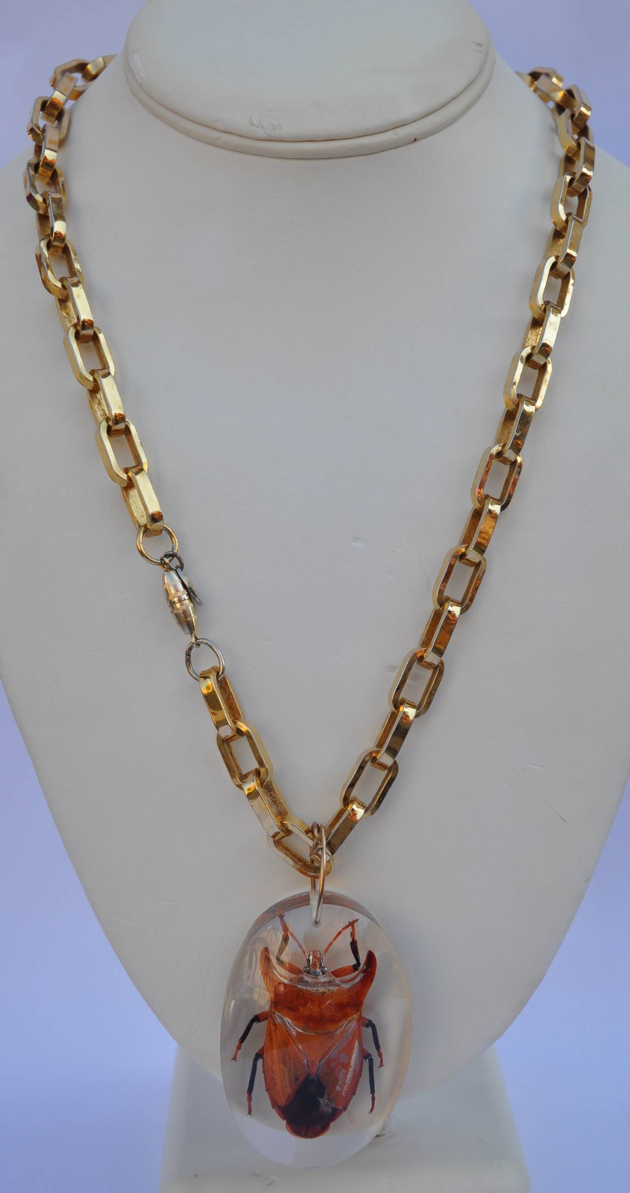         Vendome's  wonderfully wicked thick gilded gold-link chain necklace is accented with a large amber-hue globe as well as a huge lucite-covered fossilized "Bug" pendant.
         The gilded gold necklace measures 30" in length,