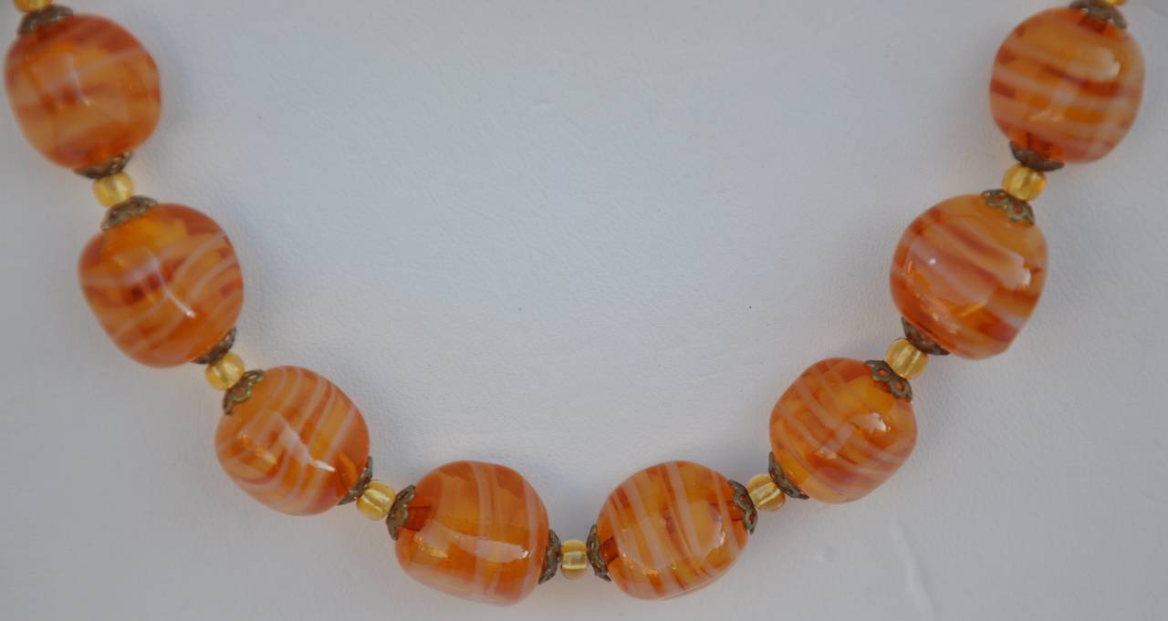 These multi-size amber-tone glass beads are paired with silver hardware and accented with micro seed glass beads in-between. The total length measures 17".