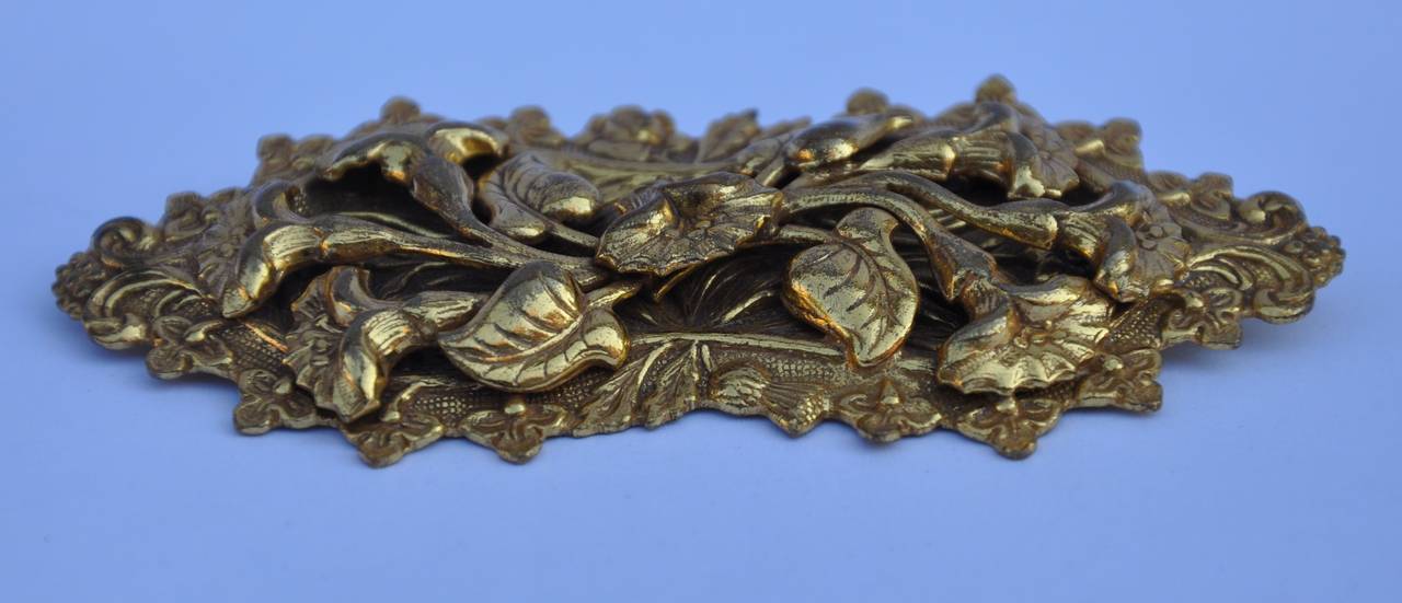 This wonderful large gilded gold vermeil finish brooch is detailed with swirls of florals and leafs. The length across measures 3 1/2", height is 1 1/2", depth is 2/8".