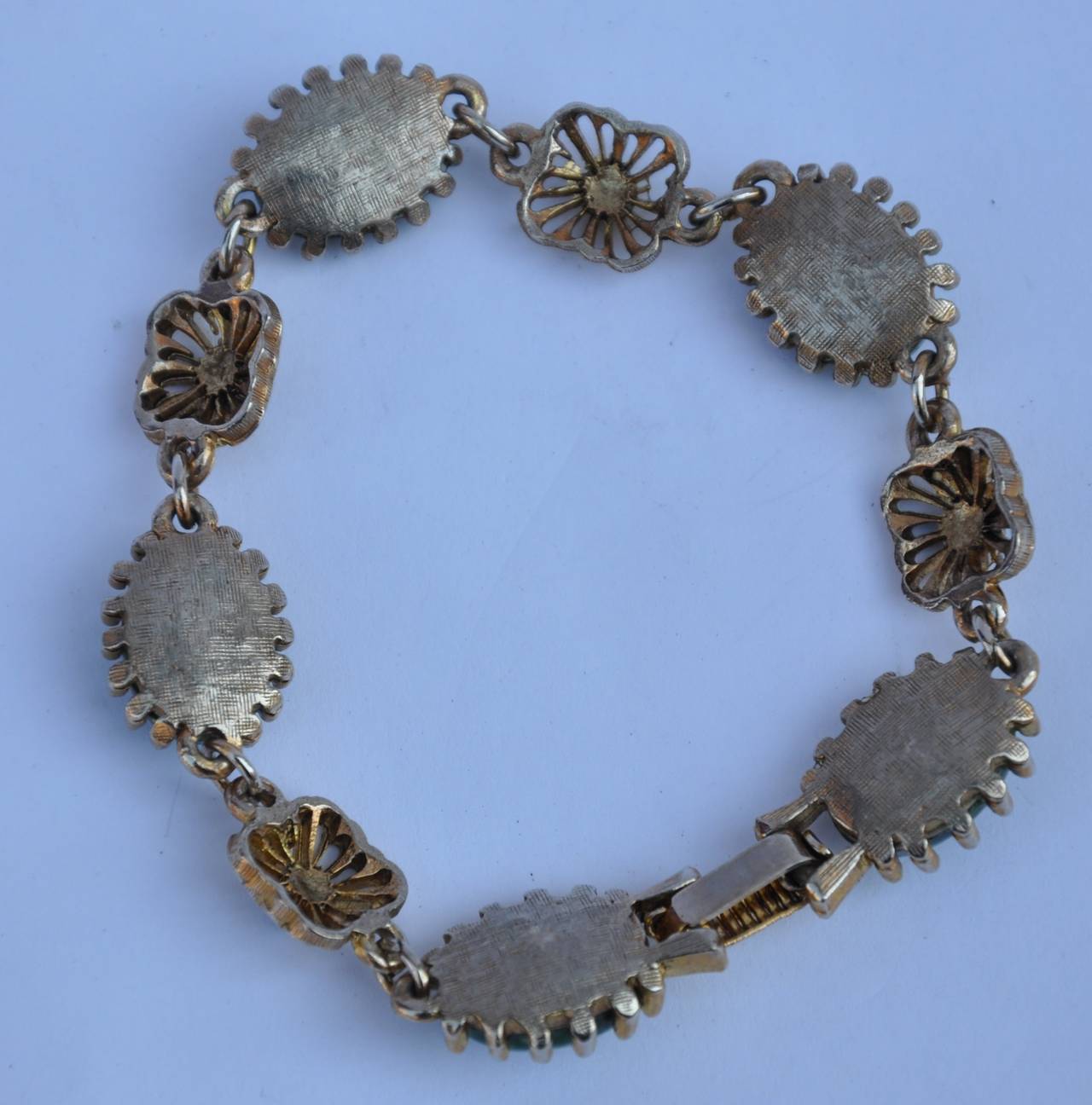 Detailed gold-tone hardware bracelet is accented with "jadeite" stones and measures 7" in total length and 1/4" in width.