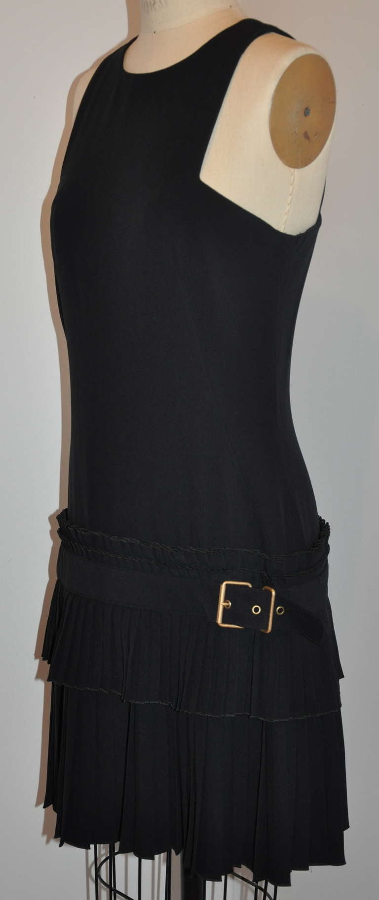 This wonderfully wicked Alexander McQueen cut-out two-tiered black dress is fully lined with black silk. Dress is accented with a black belt of same material and finished with a brass buckle.
   The front length measures 32 1/2