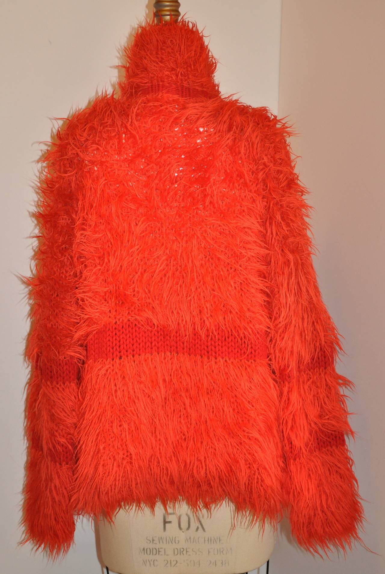 Die kühne rote Pulloverjacke von Issey Miyake ist mit braunem Kalbslederbesatz entlang des Verschlusses und Hornknöpfen akzentuiert. Der 5 1/2