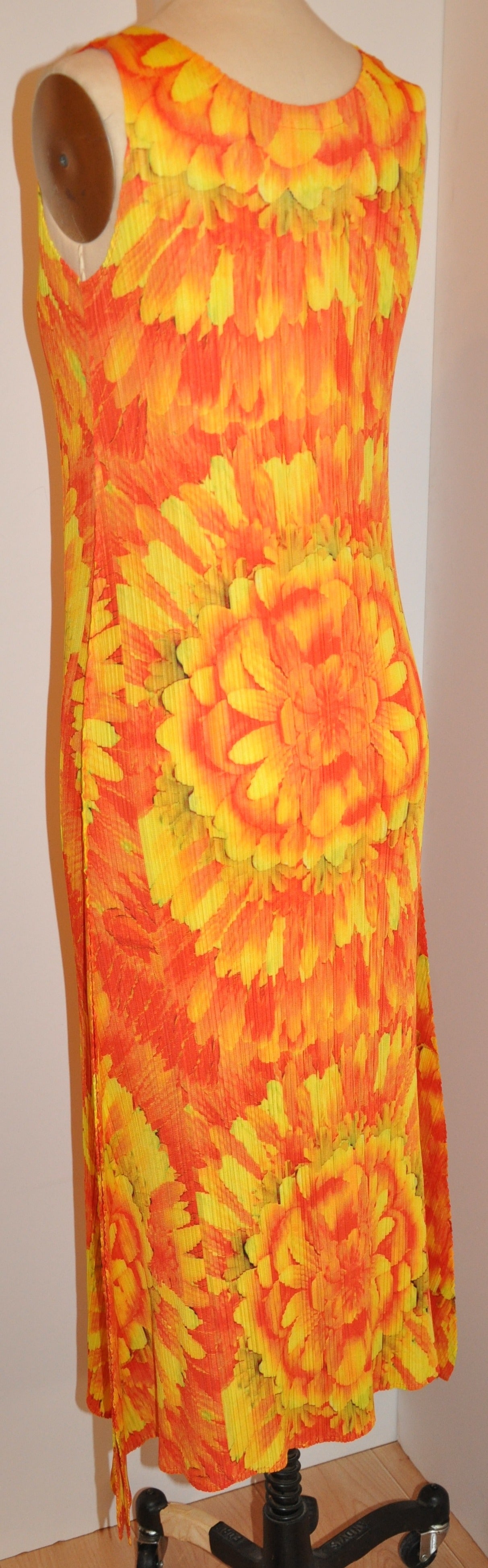 La robe longue sans manches à fleurs plissées, signée Issey Miyake, aux couleurs audacieuses de mandarine et de jaune, mesure 43