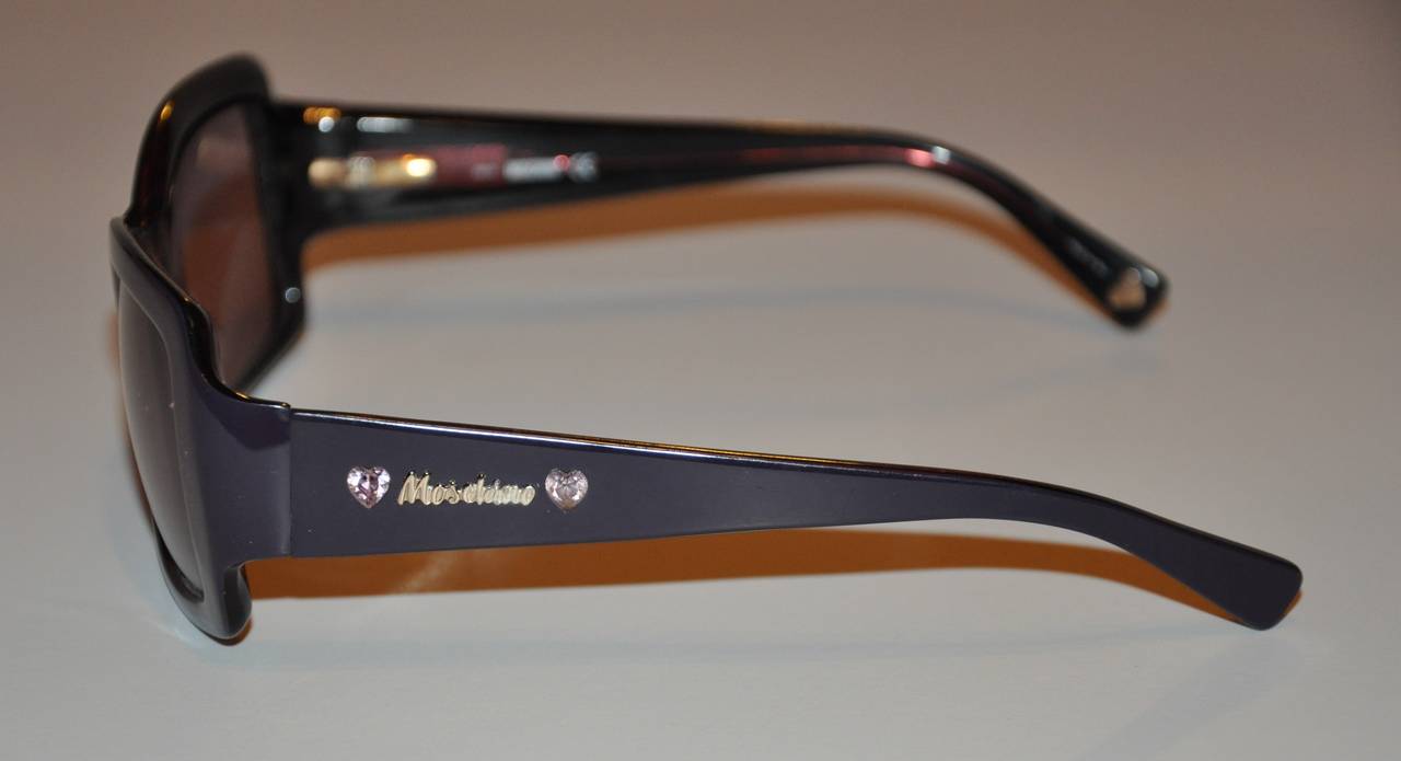 Moschino Sonnenbrille aus dickem schwarzem Lucite mit herzförmigen Kristallen an den Bügeln der Brille. Auch die Armspitzen sind mit goldenen Hardware-Herzen im Lucite hervorgehoben. Die Breite beträgt 5 5/8