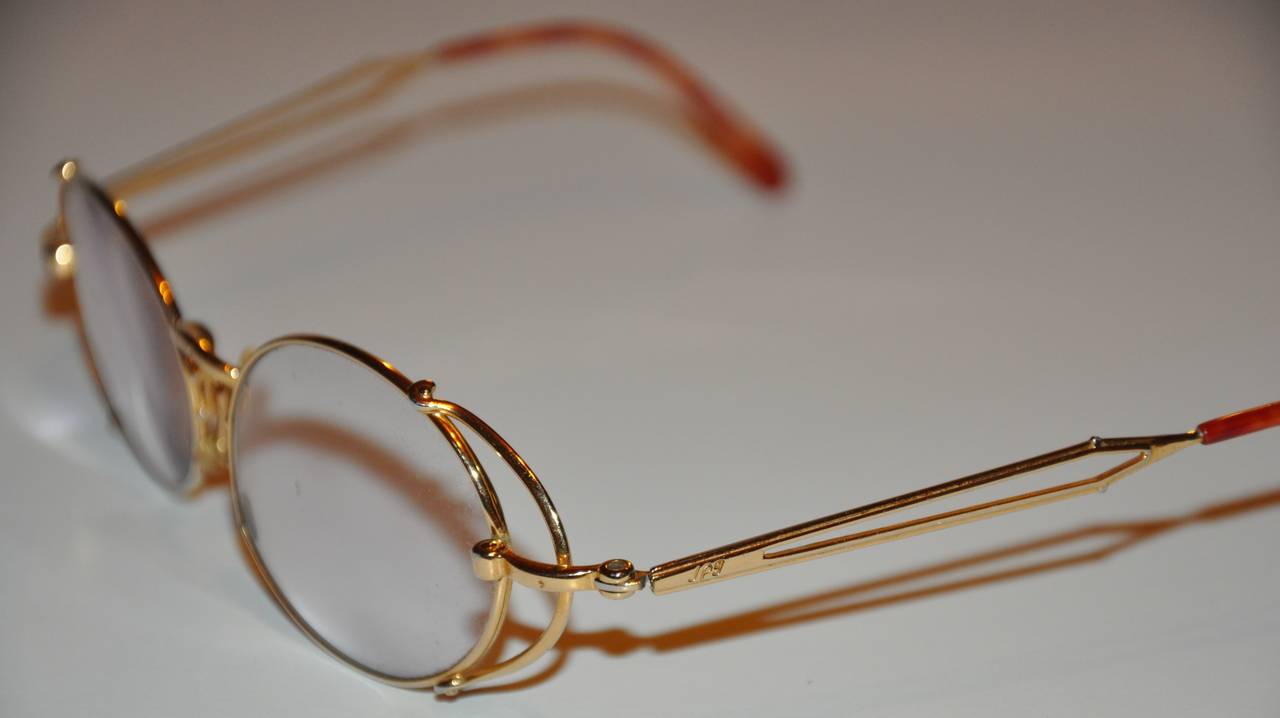 Jean Paul Gaultier detailed gold hardware glasses are accented with tortoise shell tips along the arms. The center-front has the 