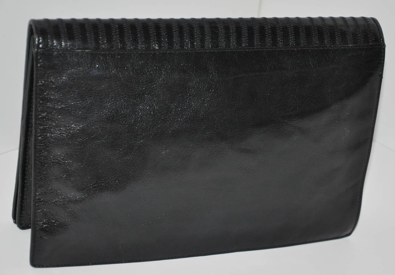 Fendi black calfskin clutch is wonderfully detailed with embroidery on the front flap. The interior is fully lined along with a zippered compartment if needed. On the interior of the flap is a magnetic closing for added protection when using.
