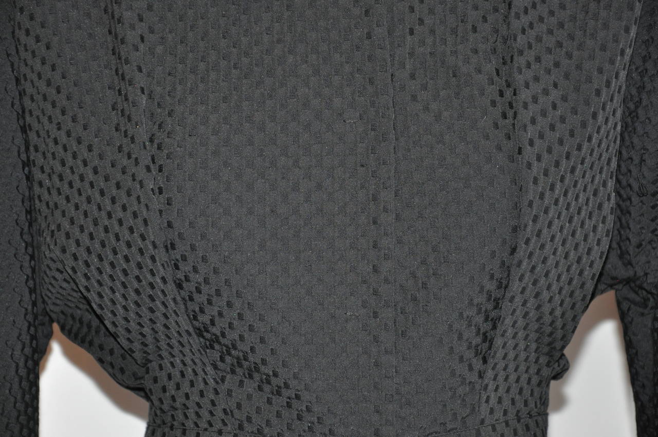        La giacca peplo Moschino nera in misto cotone completamente foderata è caratterizzata da una leggera manica stile dominio, a tre quarti, queste maniche sono affusolate verso i polsini. Il collare ha un'altezza di 2,3/4