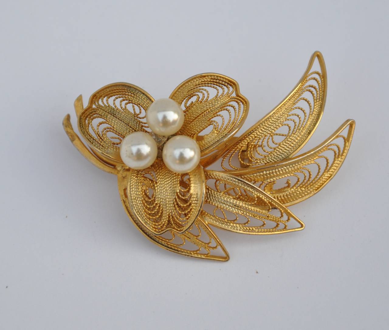 Large gilded gold filigree accented with pearls brooch measures 2" in length, 1 1/2" in height and 6/8" in depth.