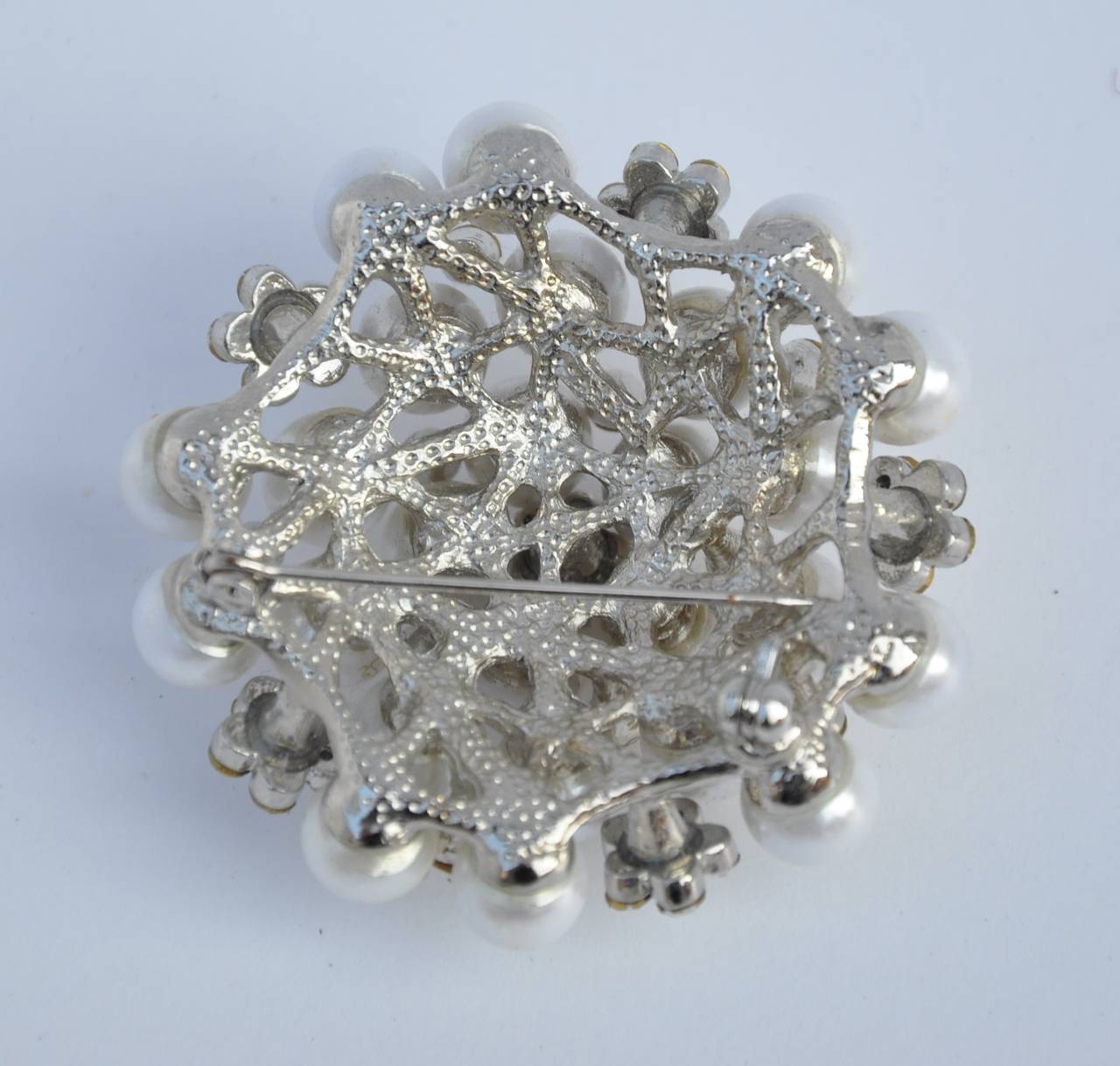 This wonderfully elegant large brooch combined with multi-rhinestones and pearls measures 2" in circumference with a depth of 3/4". Pearls and rhinestones are set in polish silver hardware for this elegant brooch.