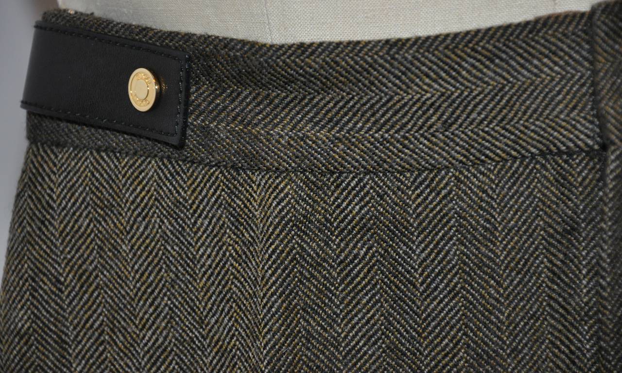 Gucci black and cream wool herringbone trousers are accented with calfskin leather as well as gold hardware on the waistband. The gold hardware is etched with Gucci's signature name with the calfskin leather finished with detailed top-stitching.
  