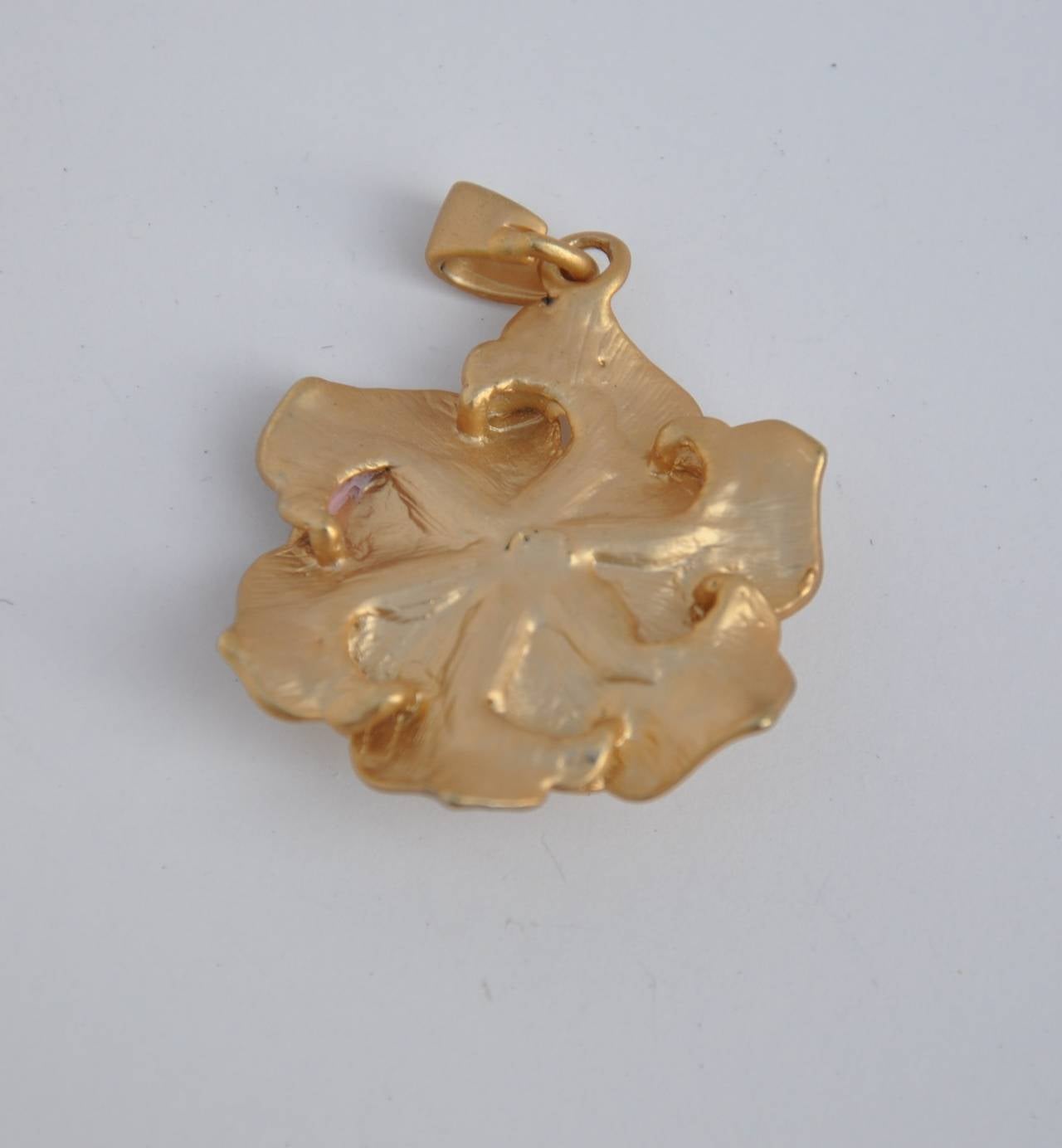 Gilded gold vermeil finished floral pendant is accented with rhinestones and measures 2" in height, 3/8" in length and 3/8" in depth.