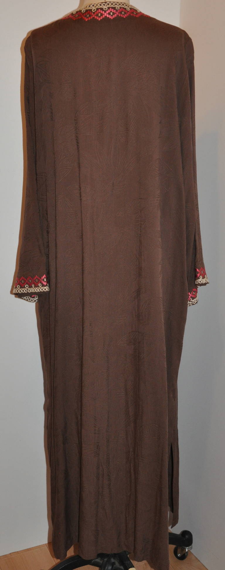 Oscar de la Renta's wonderful coco-brown silk caftan is detailed with silk threads of fuchsia and tan and hand-embroidered along the front, neck and sleeve's cuffs. And finished with swirls of beige.
   The shoulder measures 16