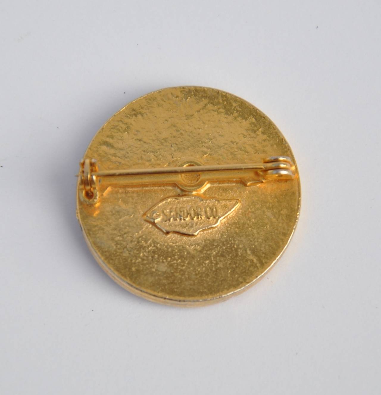 Sandor & Co. gilded gold accented with enamel "button" brooch measures 1 1/8" in circumference, with a depth of 1/8". The brooch is signed on the backside.