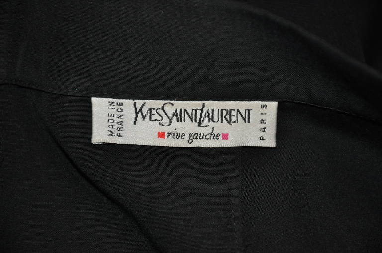 La laine noire printanière signée Yves Saint Laurent rive gauche peut être portée pendant les quatre saisons. Entièrement doublé de soie noire, le dos comporte une seule poche encastrée. L'avant comporte deux poches encastrées sur les côtés.
  