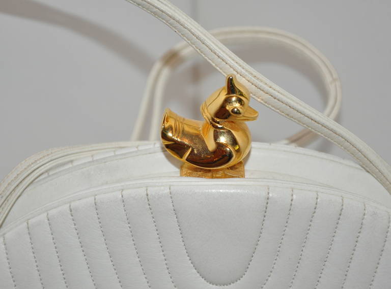 A rare, early Judith Leiber for Saks Fifth Avenue off-white calfskin round shoulder bag is highlighted with detailed stop-stitching throughout the bag, and accented with a gilded gold 