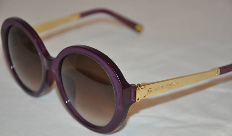 This wonderfully whimsical irresendent deep purple round sunglasses from Louis Vutton are accented with gold hardware. Their signature name is engraved on the gold hardware on both arms and gold hardware tips included on the arm's tips.