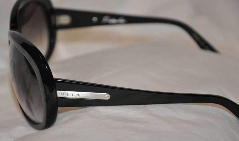 Les énormes lunettes de soleil DITA en lucite noire sont agrémentées de matériel argenté et du nom de la signature DITA sur les branches. 
   Le devant mesure 5 1/2