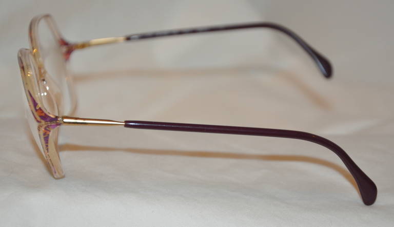 Les lunettes en lucite de Silhouette sont transparentes avec des tourbillons de violettes multicolores et finies avec un embout en lucite marron chaud sur les branches. Le cadre est renforcé par des éléments dorés à l'intérieur de la lucite.
   Le