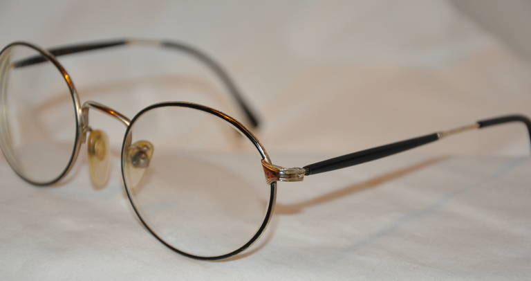 Ralph Lauren black with gold hardware round rimed glasses have detailed engravedetching on top. Arms are finished with black lucite tips.
   The front measures 5