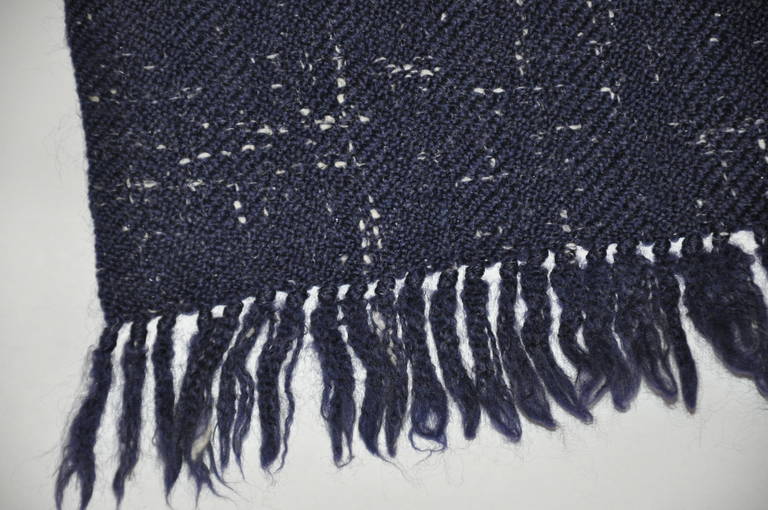 Geoffrey Beene's handloomed of 100% lambswool in navy is accented with specks of gray and creams. Ends are finished with fringe and measures 65