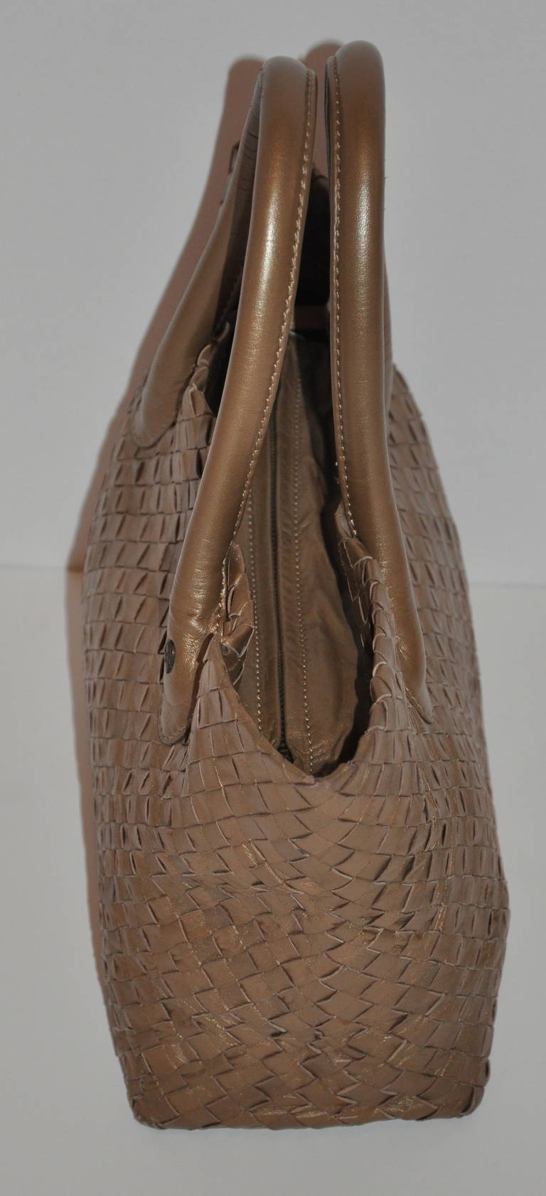 Helen Kaminski (Australia) bronze calfskin woven zippered top tote is fully lined along with an interior zippered compartment. There are six (6) brass hardware foot along the bottom for better wear.
   The top zipper measures 11