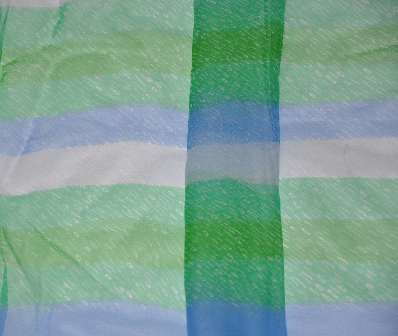 L'écharpe en mousseline de soie à rayures multicolores de Vera, composée de bleus, de bruns et de blancs, est finie avec des bords roulés à la main. L'écharpe mesure 14